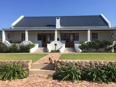 a house with a dog sitting in front of it at Endless Vineyards at Wildekrans Wine Estate in Botrivier