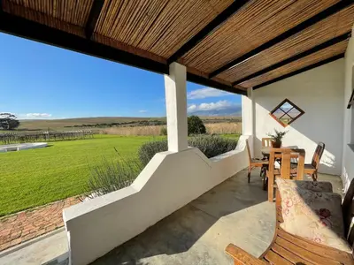 a porch of a house with a table and chairs at Endless Vineyards at Wildekrans Wine Estate in Botrivier