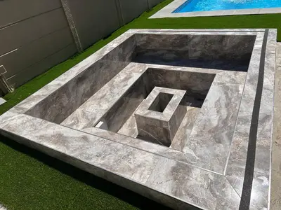 a large stoneolith in the grass in front of a pool at Enclaves Villa in Cape Town