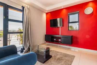 a living room with a red wall with a tv at Enclaves Villa in Cape Town