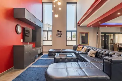a large living room with leather furniture and red walls at Enclaves Villa in Cape Town