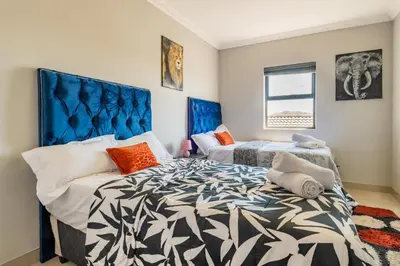 a bedroom with two beds and a blue headboard at Enclaves Villa in Cape Town
