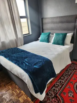 a bedroom with a large bed with a blue blanket on it at Excel accommodation in Cape Town