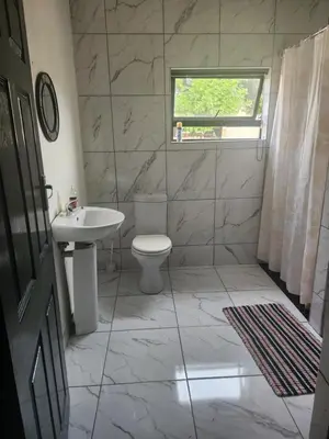 a bathroom with a toilet and a sink and a window at Excel accommodation in Cape Town