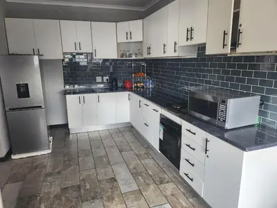 a kitchen with white cabinets and a refrigerator at Excel accommodation in Cape Town