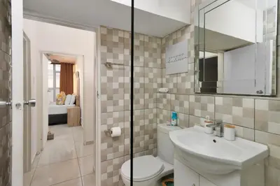 a bathroom with a toilet and a sink and a mirror at Seaside Sunsets in Strand