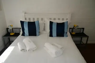 a white bed with towels and pillows on it at Bradclin @ York in Cape Town