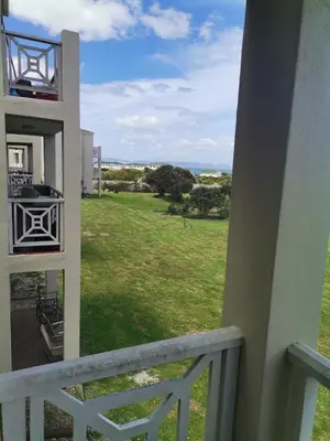 a balcony with a view of a field of grass at Beach Club 47 Hermanus in Hermanus
