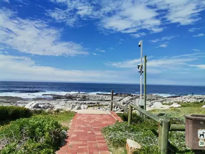 a brick path leading to the beach with the ocean at Beach Club 47 Hermanus in Hermanus