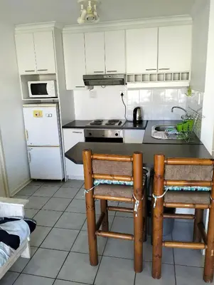 a kitchen with a counter and two chairs in it at Beach Club 47 Hermanus in Hermanus