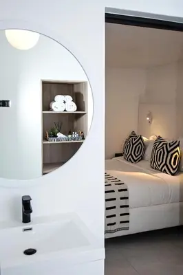 a white bedroom with a bed and a mirror at Paarl Hideaway in Paarl