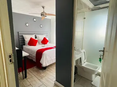 a bedroom with a bed with red pillows and a toilet at 57onWYNNE in Cape Town