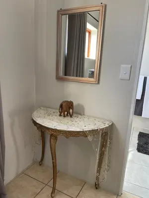 a small dog sitting on a table under a mirror at Sophia’s Cottage in Cape Town