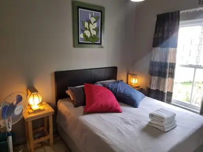 a bedroom with a bed with red and blue pillows at Strawberry fields Tranquility in Cape Town