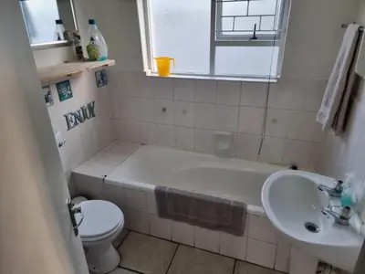 a bathroom with a tub and a toilet and a sink at Strawberry fields Tranquility in Cape Town