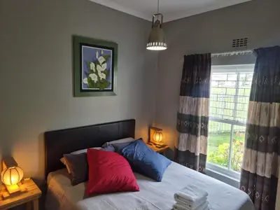 a bedroom with a bed with red and blue pillows at Strawberry fields Tranquility in Cape Town
