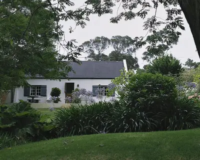 a white house with a garden in front of it at Wildekrans Country House in Botrivier