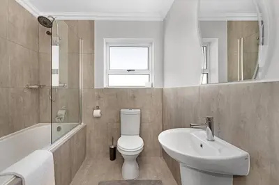 a bathroom with a white toilet and a sink at Elegant, Spotless 2 Bed For Enchanted Stays in Cape Town