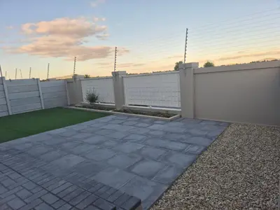 a backyard with a white fence and a lawn at Elegant, Spotless 2 Bed For Enchanted Stays in Cape Town