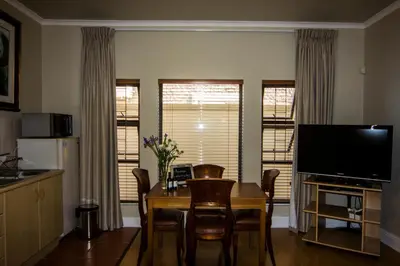 a living room with a dining room table and a television at Casa Mia Guesthouse in Table View