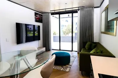 a living room with a glass table and a couch at Modern apartment in Century City in Cape Town
