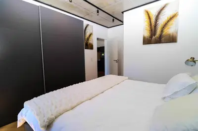 a bedroom with a white bed and a painting on the wall at Modern apartment in Century City in Cape Town