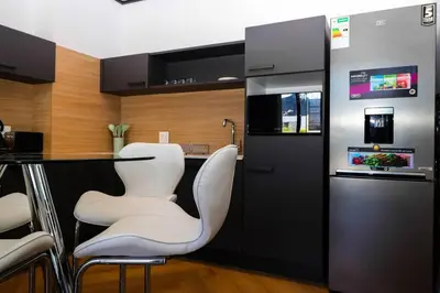 a kitchen with a bar with white chairs and a counter at Modern apartment in Century City in Cape Town