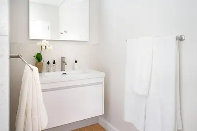 a white bathroom with a sink and a towel at Middedorp Apartments in Stellenbosch