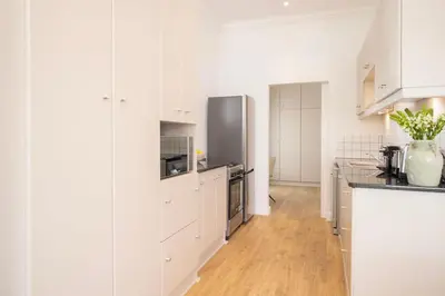 a kitchen with white cabinets and a stainless steel refrigerator at Middedorp Apartments in Stellenbosch