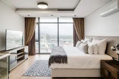 a bedroom with a large bed and a large window at Belina - Crystal Towers Presidential Penthouse in Cape Town