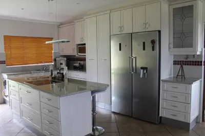 a kitchen with white cabinets and a stainless steel refrigerator at Firlands Farmhouse 179A with a view in Sir Lowry Pass