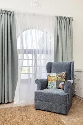 a blue chair with a pillow in front of a window at Casa Familia in Hermanus