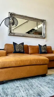 a brown couch in a living room with a mirror at Meerendahl Luxury Apartments at Tyger Lake in Cape Town