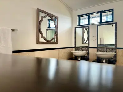 a bathroom with two sinks and two mirrors at Meerendahl Luxury Apartments at Tyger Lake in Cape Town