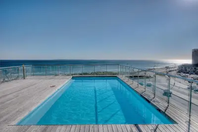 a swimming pool on a deck next to the ocean at Horizon Bay 1603 by HMH in Cape Town