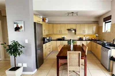 a kitchen with a wooden table and a refrigerator at Waterside Townhouse in Cape Town