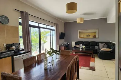 a kitchen and living room with a long wooden table at Waterside Townhouse in Cape Town