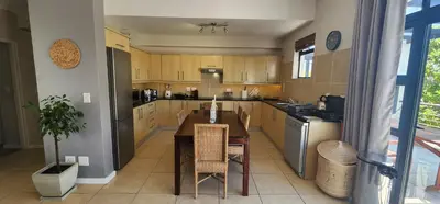 a kitchen with a wooden table and a dining room at Waterside Townhouse in Cape Town