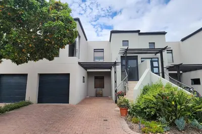 a white house with two garage doors and a driveway at Waterside Townhouse in Cape Town