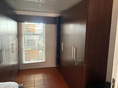 a bedroom with wooden cabinets and a window in a room at Harmony Lawson Road in Cape Town