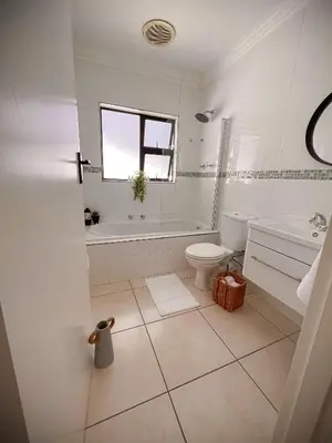 a bathroom with a tub and a toilet and a sink at Spacious beachfront Townhouse w garage, Blouberg in Bloubergstrand