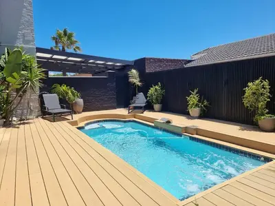 a swimming pool on a wooden deck with a patio at @5 on Lincoln in Cape Town