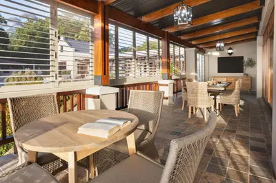 a dining room with a table and chairs and windows at Avemore Manor House wood fired hot tub magical views and full Backup power in Stellenbosch
