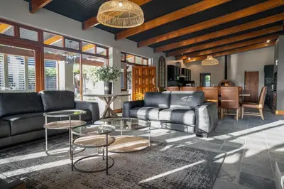a living room with couches and tables and a kitchen at Avemore Manor House wood fired hot tub magical views and full Backup power in Stellenbosch