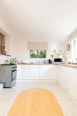 a kitchen with white cabinets and a wooden floor at Newly Renovated - Stellenbosch Farm Cottage in Stellenbosch
