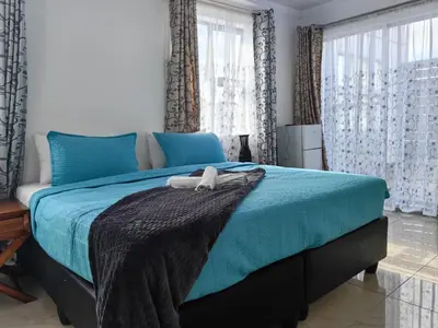 a bedroom with a blue bed with a blanket on it at Essential Lodge23 in Cape Town