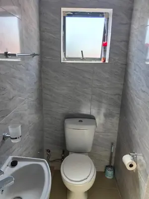 a bathroom with a toilet and a sink and a window at Essential Lodge23 in Cape Town