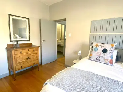 a bedroom with a bed and a dresser and a mirror at Stay on Main 1 in Paarl