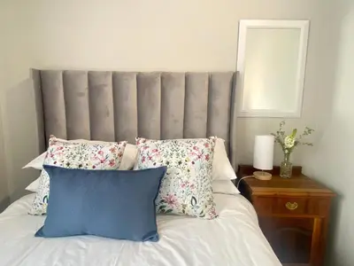 a bed with a gray headboard and pillows on it at Stay on Main 1 in Paarl