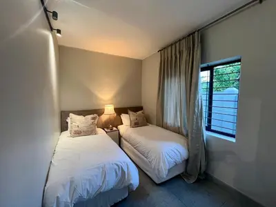 two beds in a room with a window at Stay on Main 1 in Paarl